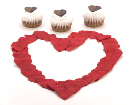 A love heart shape of Petals with three Valentines cakes.の写真素材