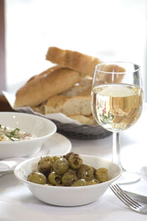 Some white Wine with Bread and a bowl of Olivesの写真素材
