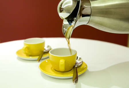 A coffee pot with yellow coffee cups.の写真素材