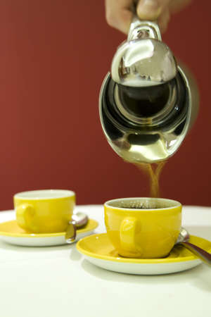 A coffee pot with yellow coffee cups.の写真素材