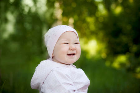 Happy little girl in a cap laughing in the summer outdoorsの写真素材