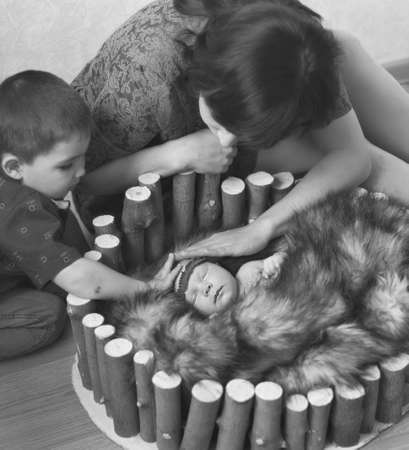 mom and brother look at a newborn baby and Pat him on the headの写真素材