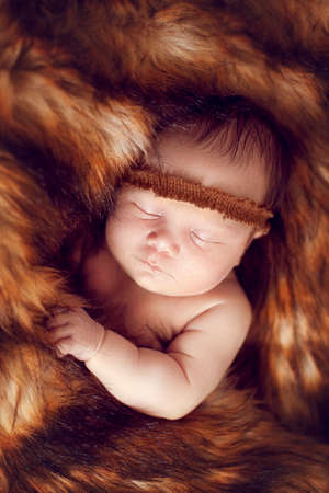 newborn baby sleeping peacefully on the red fur, warmed by the fur of a Foxの写真素材