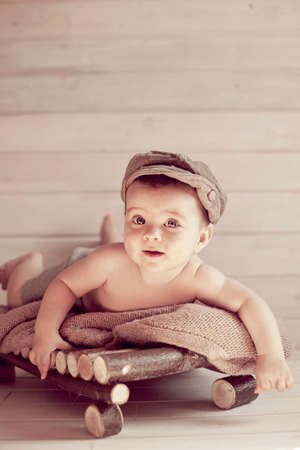 Adorable happy baby boy in a bright room. The baby in the hat smiling looking at camera. Retro styleの写真素材