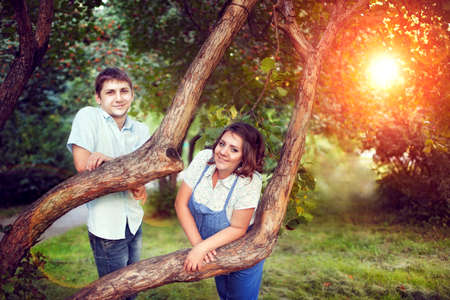 Happy couple expecting a baby walks in summer in a beautiful Park. Pregnant woman laughing with her husband, vacationing natureの写真素材