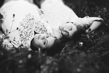 Happy couple waiting baby lying in the grass in the field. Pregnant woman with folk costume and her husband enjoy the romance in natureの写真素材