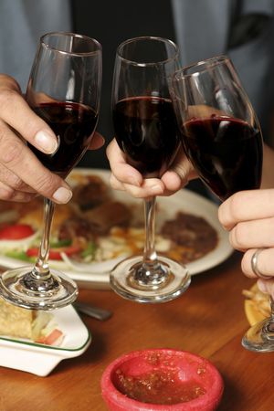 Three people toasting at a Mexican restaurant. Shallow dof. Foreground/background blurred. Focus on...