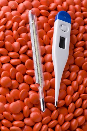 object on red - Medical Tablets and thermometer close up