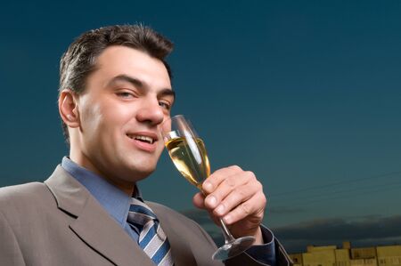 man in a suit against the evening sky with a glass of champagneの写真素材