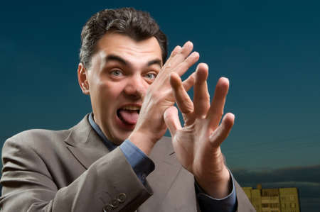 man in a suit against the evening sky shows tongueの写真素材