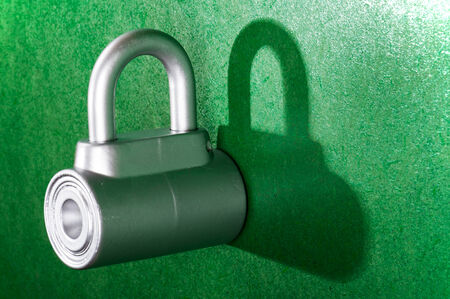 chrome metal padlock - on green backgroundの写真素材