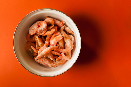 raw shrimp on a metal bowl on red backgroundの写真素材