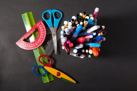 pens pens pencils ruler and scissors in a plastic jar on a dark backgroundの写真素材