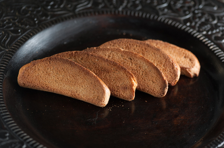 crackers rusks in a carved wooden plate on a dark backgroundの写真素材