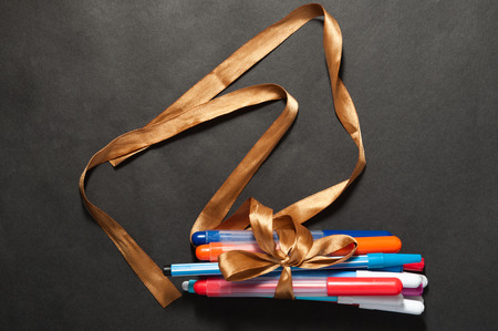 pen markers pencils tied with tape on a dark backgroundの写真素材