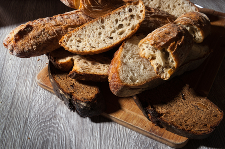 cuttind bread cereal baguette and fig bread with prunes on wooden background