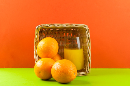 glass of juice with oranges on red backgroundの写真素材