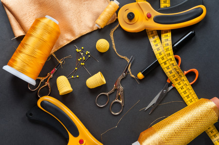 sewing tools thread with scissors and measuring tape on darkの写真素材
