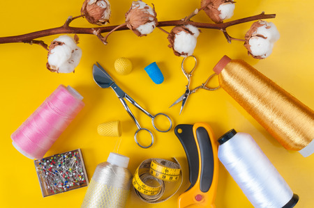 sewing items on a yellow background with a branch of wild cottonの写真素材
