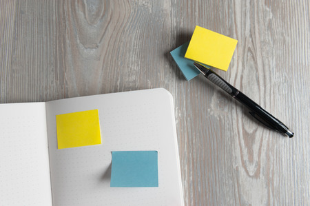 Notebook with pen and sticky notes on wood table