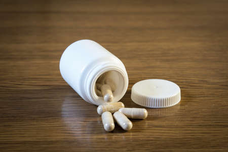 Open white jar with pills