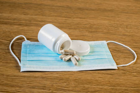 Medical mask, white jar and pills on the table stock photo