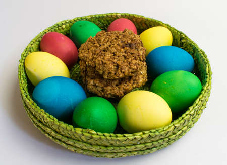 Easter eggs in a basket and nut cookies on the tableの写真素材
