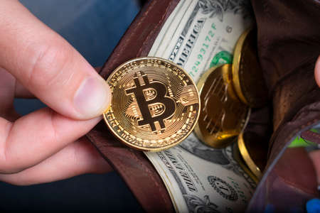 Bitcoin coin and dollar in a wallet in handの写真素材