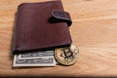 Bitcoin coin and dollar in the wallet on the tableの写真素材