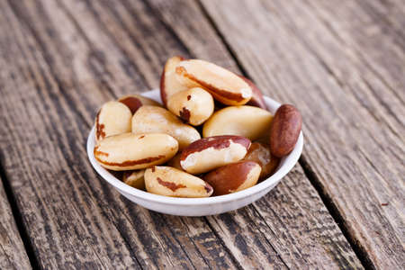 Brazil nuts on a white plate on grey background.