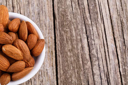 Almonds on a plate on a wooden background.の写真素材