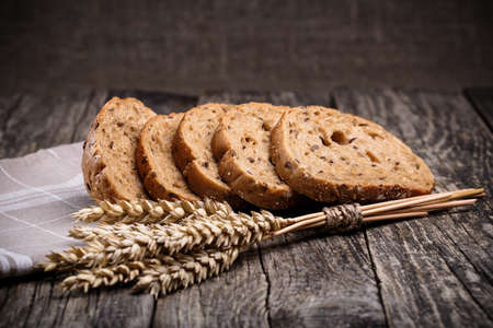 Slices of bread with rye on a wooden background.