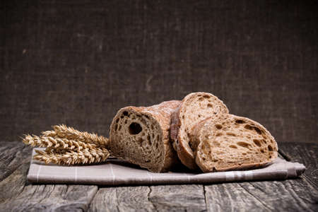 Slices of bread with rye on a wooden background.