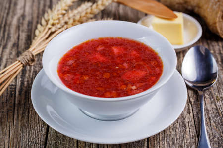 Borsch with bread on a wooden background.