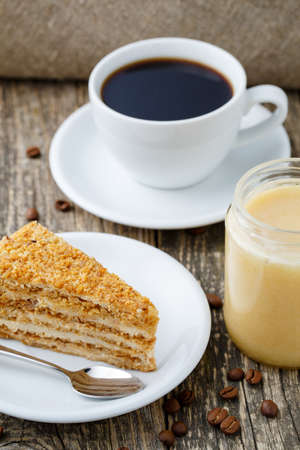 Delicious slice of honey cake and coffee on wooden background.の写真素材