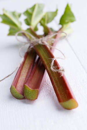 Bundle of rhubarb on white wooden table.の写真素材