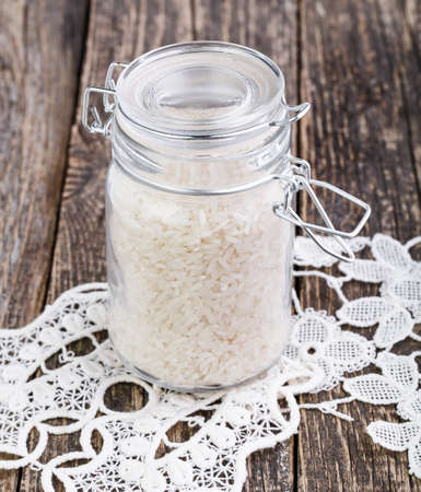 Dried rice in glass jar on wooden table.の写真素材