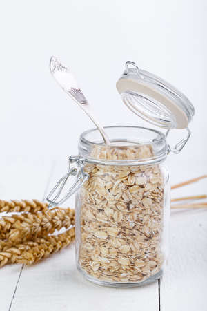 The oat flakes in jar and wheat on wooden table.の写真素材