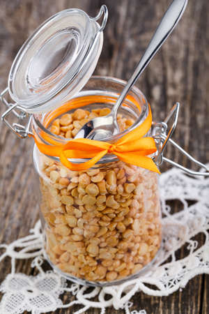 Dried peas in jar with orange ribbon on wooden table.の写真素材