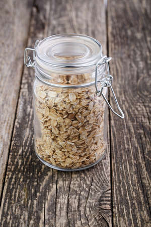 The oat flakes in glass jar on wooden table.の写真素材