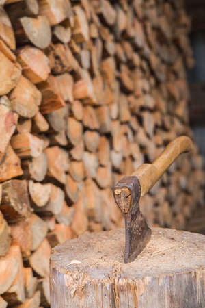 Hatchet thrusted in old stump with background of logs.の写真素材