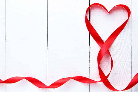 Red ribbon heart on white wooden background on valentine's day.の写真素材