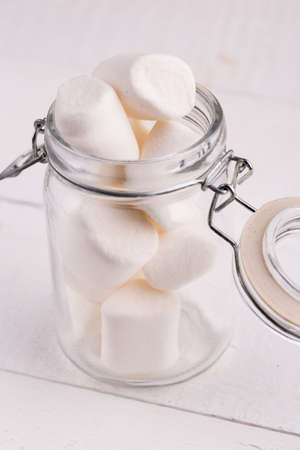 Sweet marshmallows in a glass jar on wooden table.の写真素材