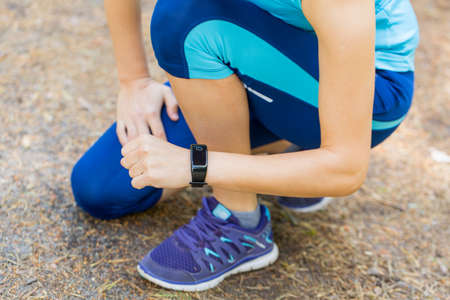 Closeup shot of young female runner arms with sports smartwatch and legs .の写真素材