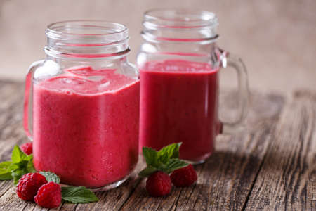 Healthy raspberry smoothie on wooden table with mint leaves.の写真素材