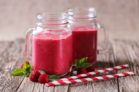 Healthy raspberry smoothie with mint leaves and drinking straw.の写真素材