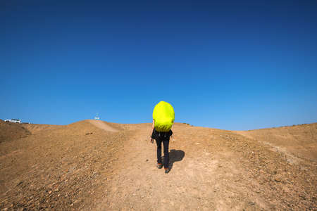Tourist at Charyn canyon in Kazakhstan. Brown hills and clear blue sky.