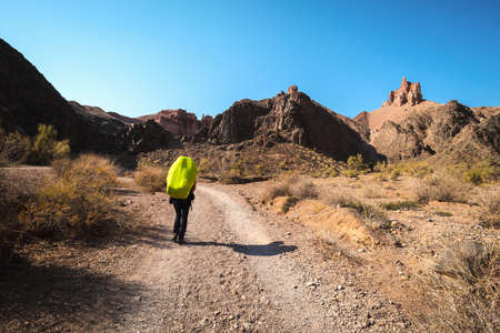 Tourist at Charyn canyon in Kazakhstan. Brown hills and clear blue sky.