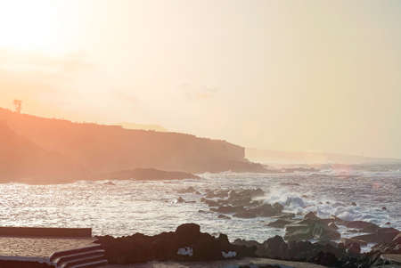 Colorful sunset over a costline of Tenerife. With a fog due to the salt air coming from the Atlantic Ocean. Garachico, Spainの写真素材