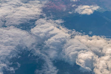 View over the clouds above Tanzania. Bright skyscape and green land beyond.の写真素材